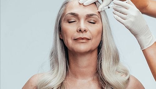 Woman receiving cosmetic treatment with syringe.