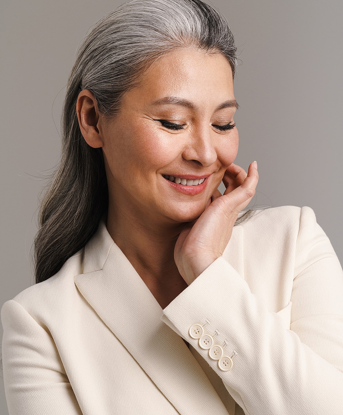 Smiling woman with gray hair, wearing a blazer.