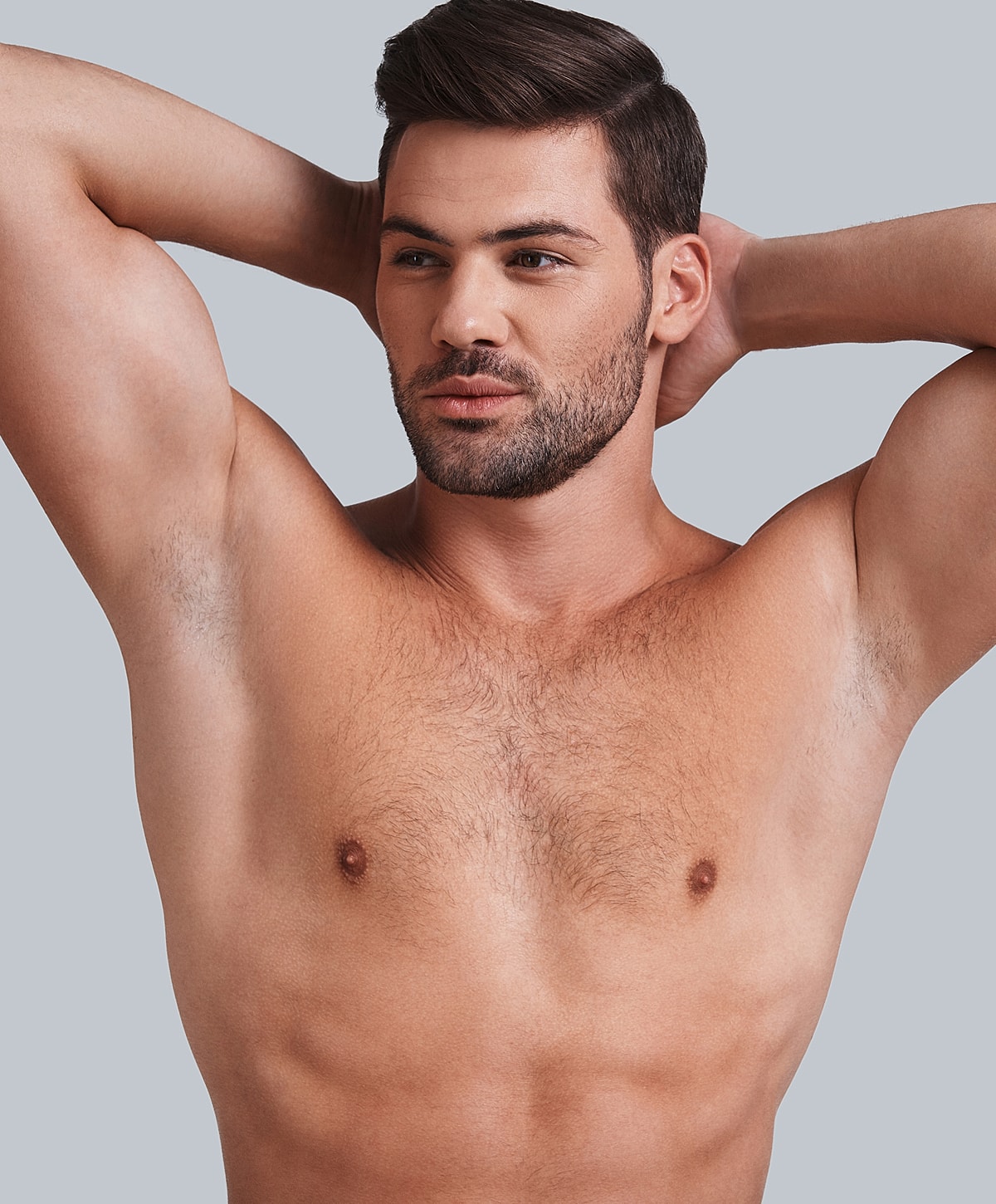 Shirtless man posing with arms behind head.