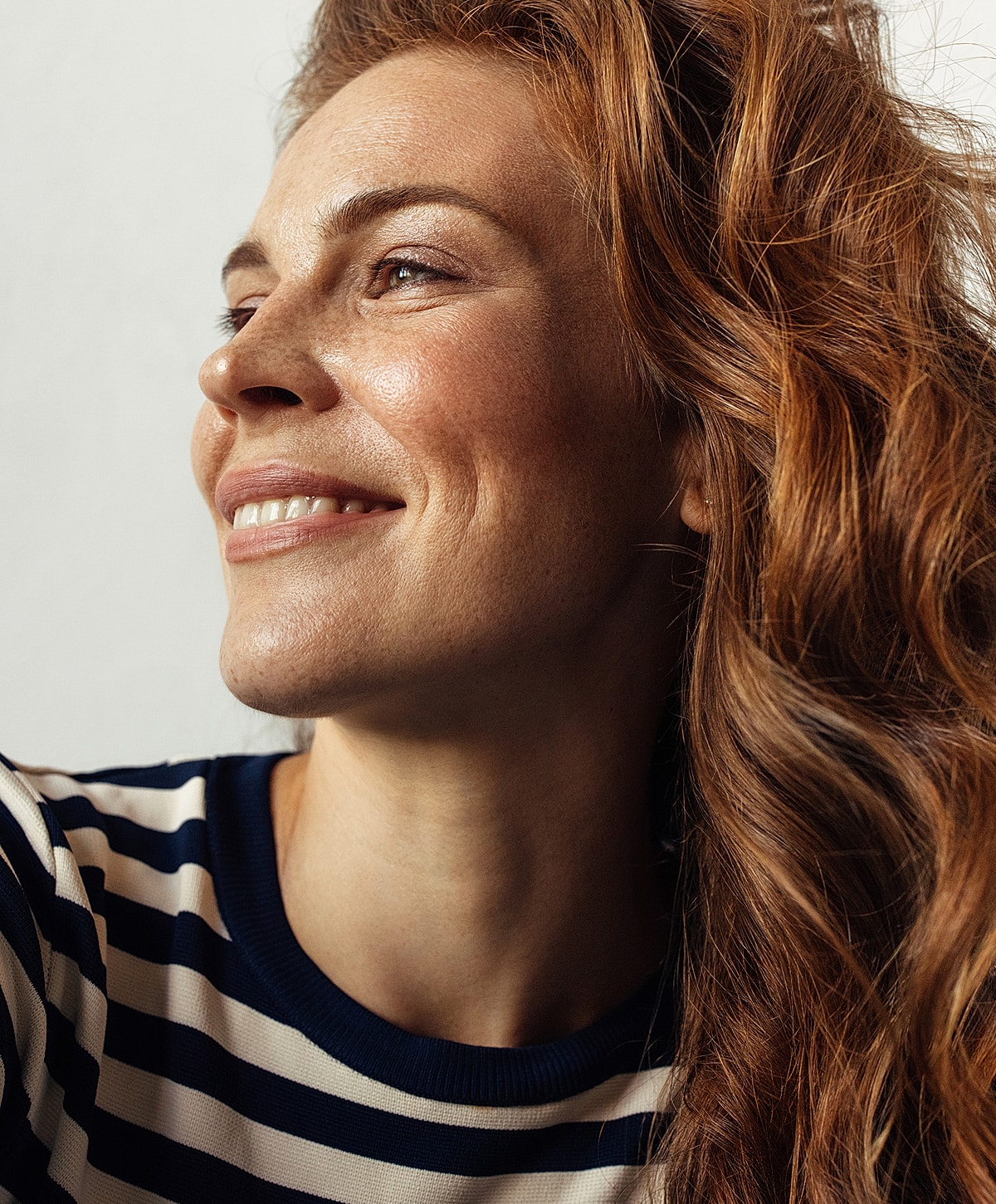 Woman with red hair smiling softly.