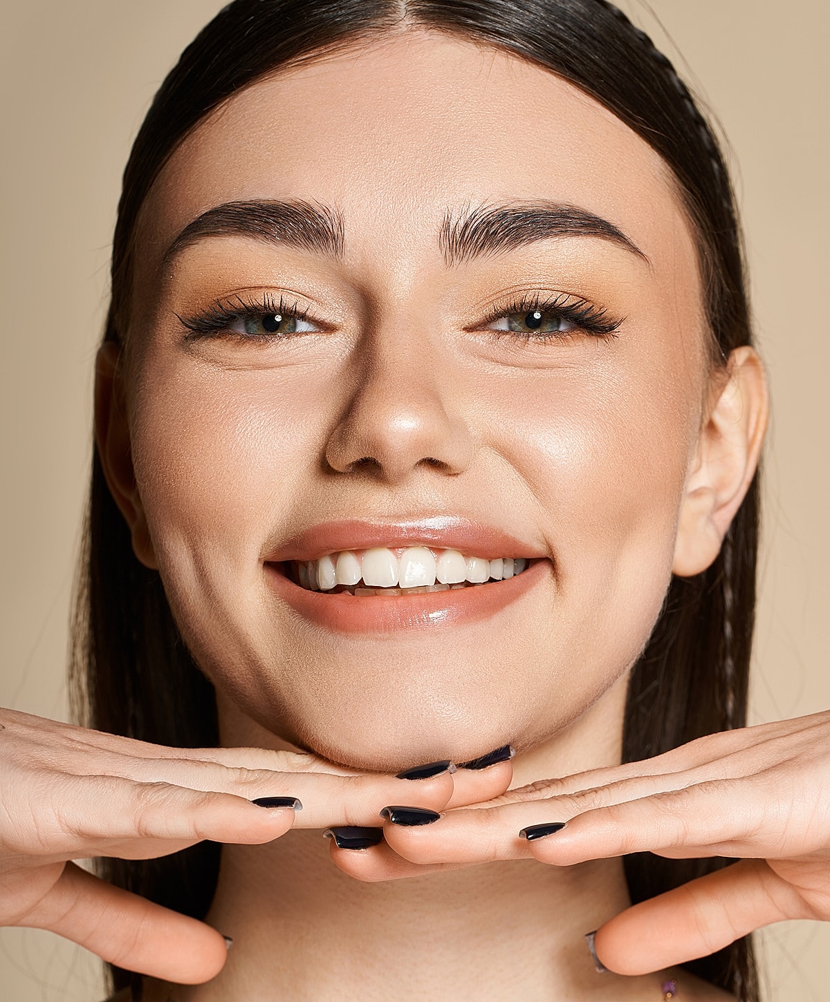 Smiling woman with hands under chin.