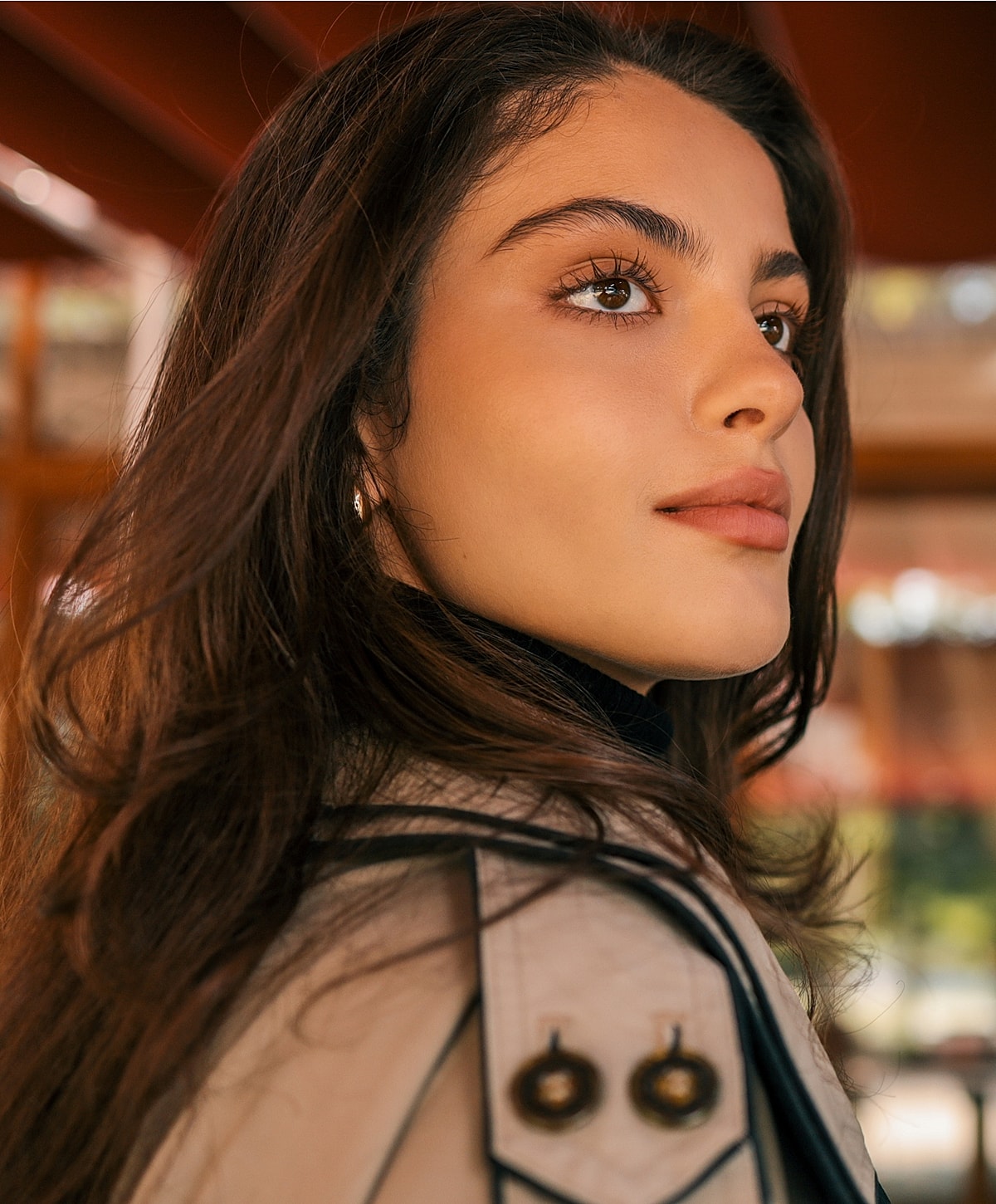 Woman with long hair, wearing a stylish coat.