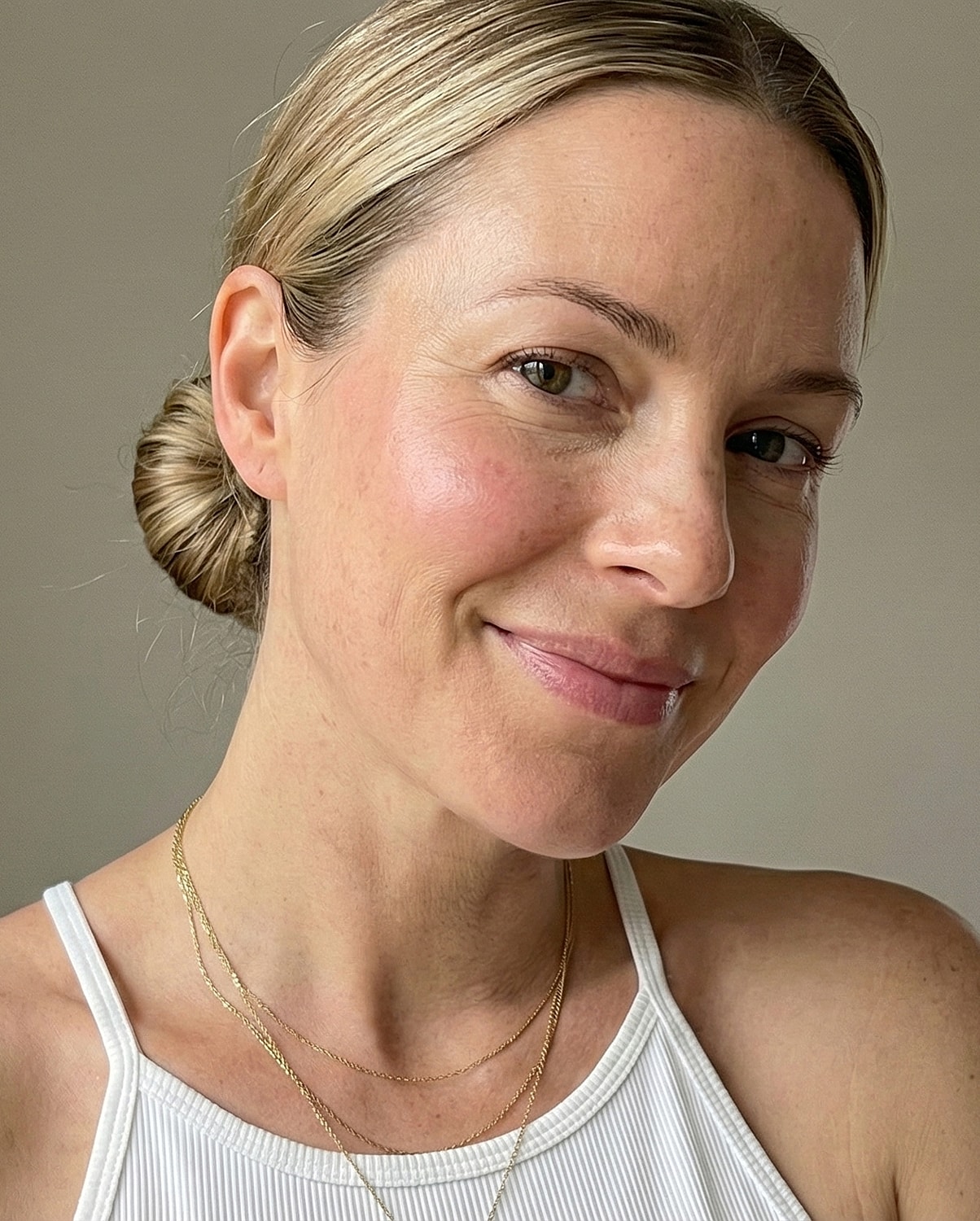 Smiling woman with blonde hair and jewelry.