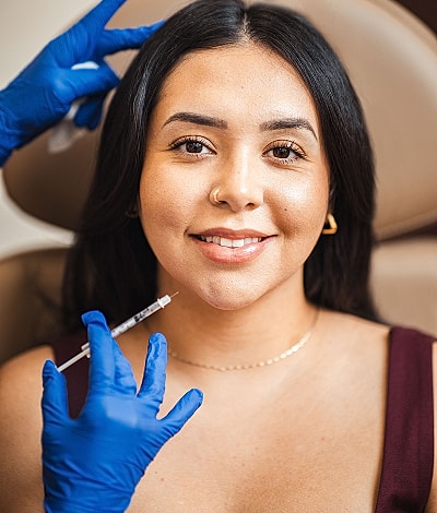 Plastic surgeon by entrance sign, smiling confidently.