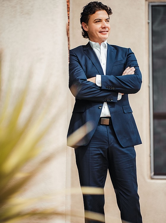 Man in suit leaning against a wall.