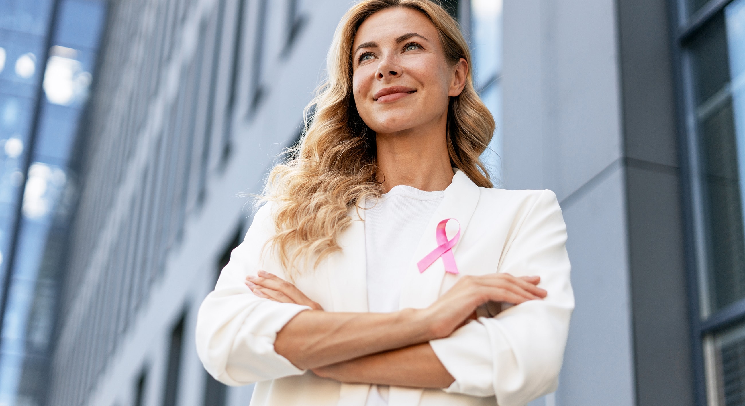 Confident woman wearing pink ribbon outdoors.