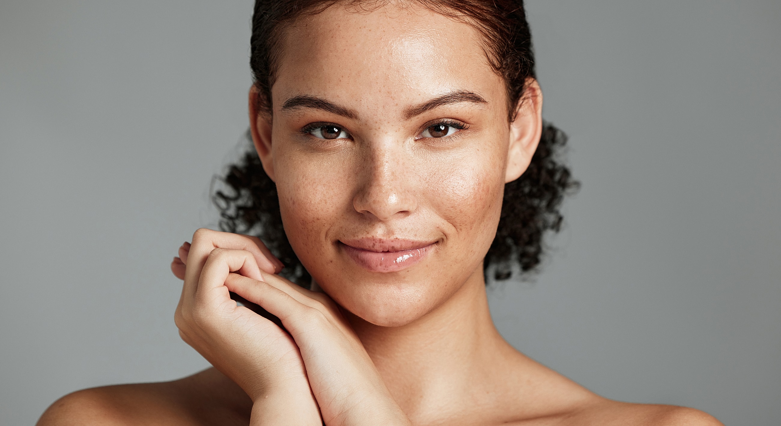 Smiling young woman with curly hair and freckles.
